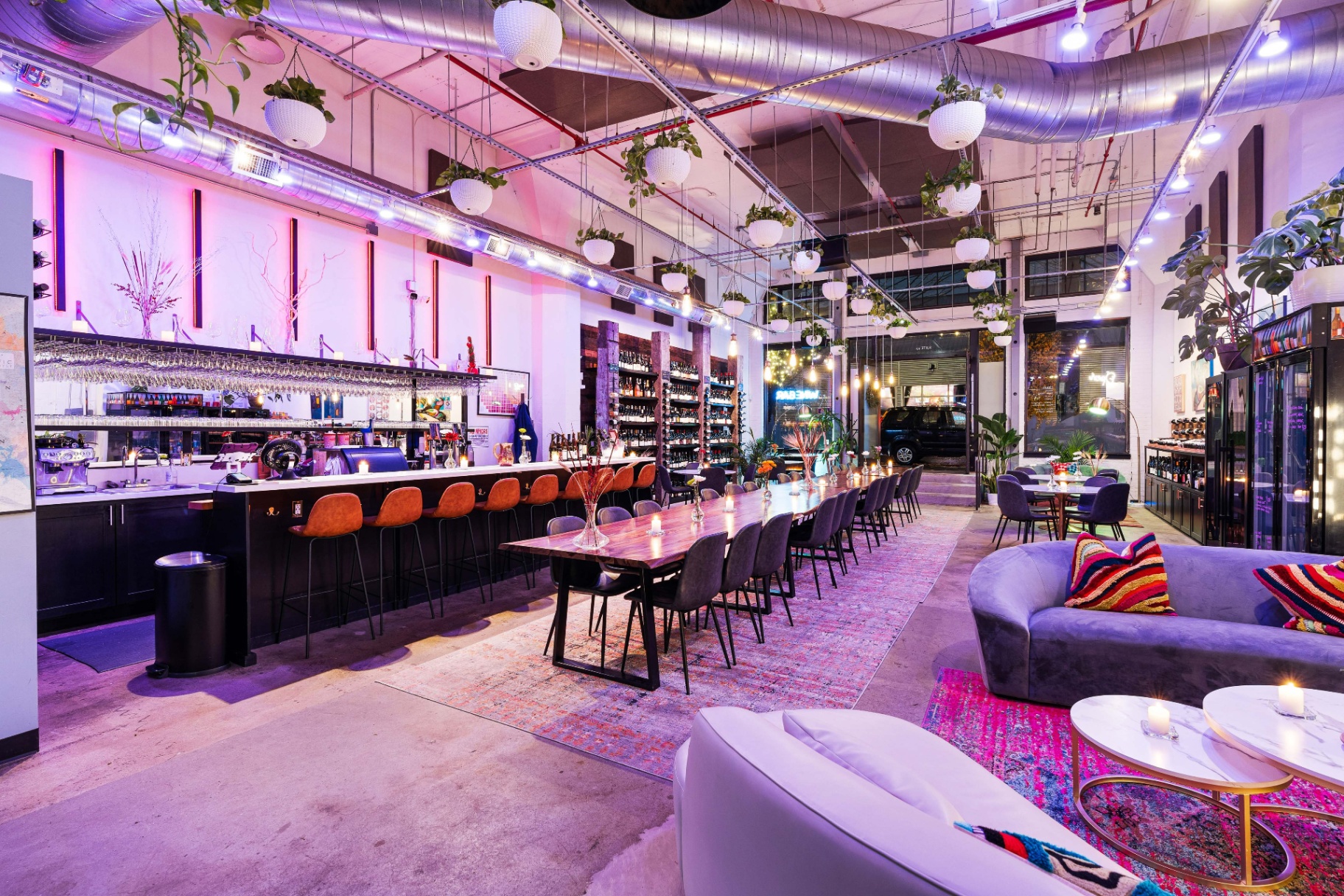 The full Backcountry tasting room — communal table, bar, and lounge under string lights.