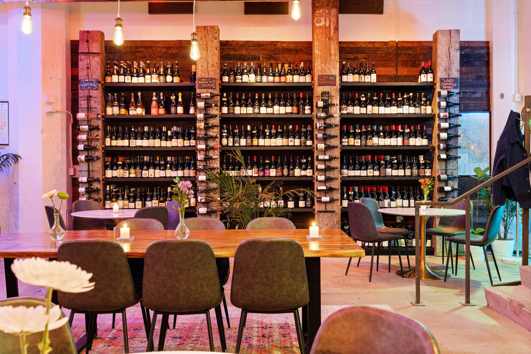 Floor-to-ceiling bottle wall framed by reclaimed timber beams.