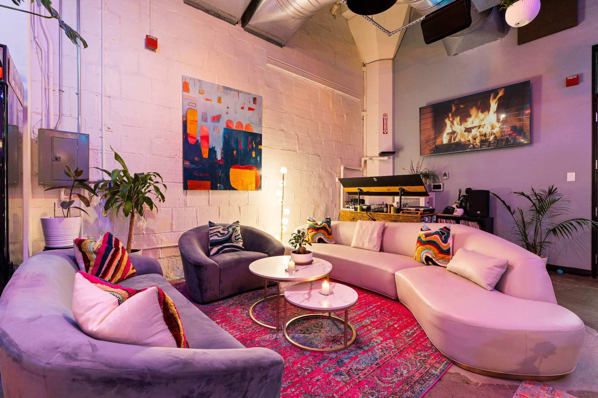 Pink velvet lounge with vinyl turntables and fireplace screen.